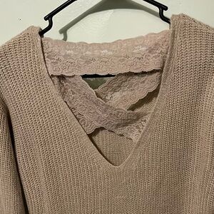 A tan knit sweater with beautiful lace bands on the back.